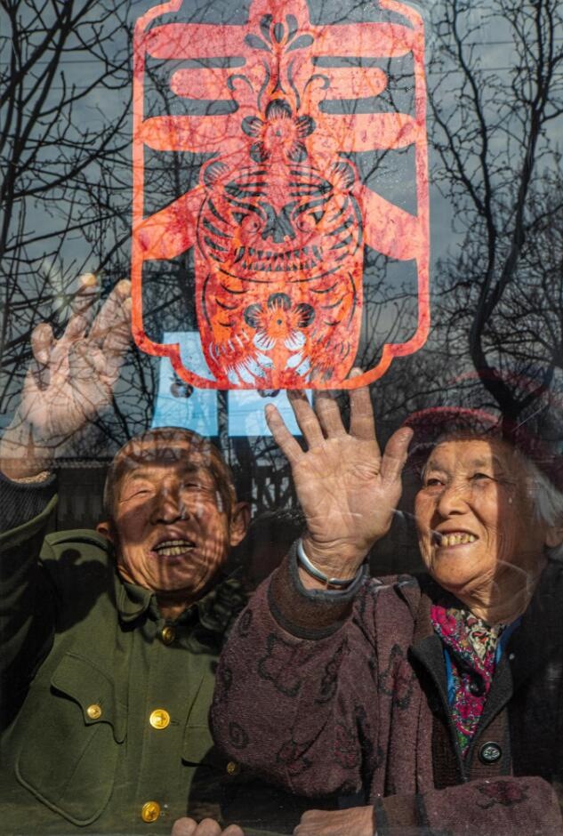 臘月里，霍州市師莊鄉(xiāng)馮南垣村村民師榮光(左)在災(zāi)后重建的新家里貼窗花。(霍州市委宣傳部供圖)