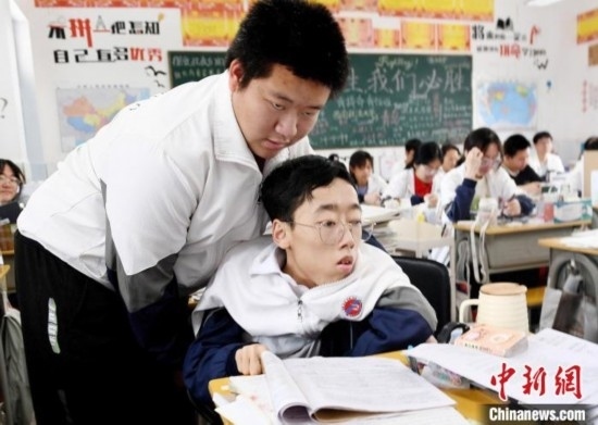 朱金祥(左)把鐘華強(qiáng)放到課堂座位上后，都要把他擺正好，確認(rèn)安全后才回到自己的座位上。 卓忠偉 攝