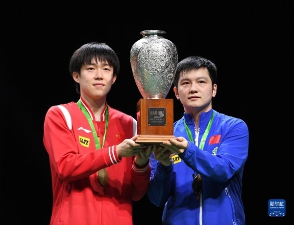 5月27日，樊振東（右）/王楚欽在頒獎儀式上高舉獎杯慶祝。當日，在南非德班進行的2023年世界乒乓球錦標賽男雙決賽中，中國組合樊振東/王楚欽以3比0戰(zhàn)勝韓國組合張禹珍/林鐘勛，奪得冠軍。新華社記者 李亞輝攝