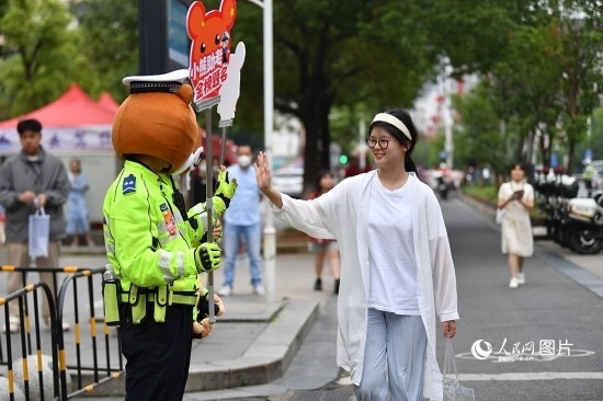 6月7日上午9時(shí)，隨著鈴聲的響起，2023年江西高考正式開(kāi)考，江西省的53.57萬(wàn)考生以縣（區(qū)）為單位隨機(jī)安排在全省256個(gè)考點(diǎn)、18968個(gè)考場(chǎng)參加高考。圖為“小熊交警”和考生擊掌鼓勵(lì)。 人民網(wǎng)記者 時(shí)雨攝