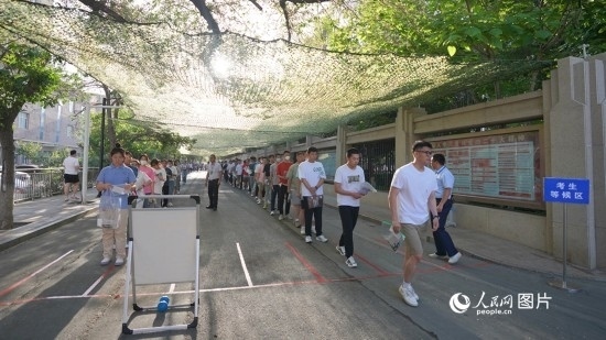 6月7日，烏魯木齊市第七十中學(xué)門(mén)口，考生們有序進(jìn)入考場(chǎng)。人民網(wǎng) 李欣洋攝