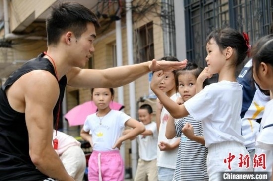 圖為大學(xué)生志愿者在組織孩子們參加體育健身活動(dòng)。廖光福 攝