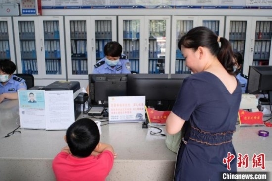 圖為一名家長正在辦證窗口前為孩子申領居民身份證。劉俊聰 攝