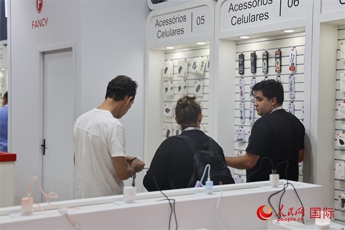 幾名參觀者在一個展臺前了解手機配件。（人民網(wǎng)記者 時元皓攝）