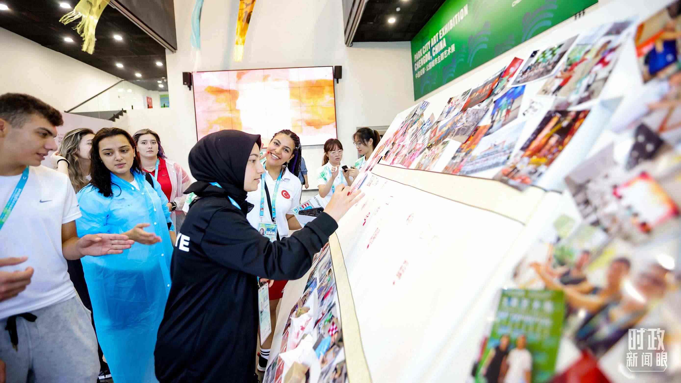 各國(guó)青年運(yùn)動(dòng)員正在參觀成都大運(yùn)村內(nèi)的“雪山下的公園城市，煙火里的幸福成都”主題藝術(shù)展。（總臺(tái)央視記者魏幫軍拍攝）