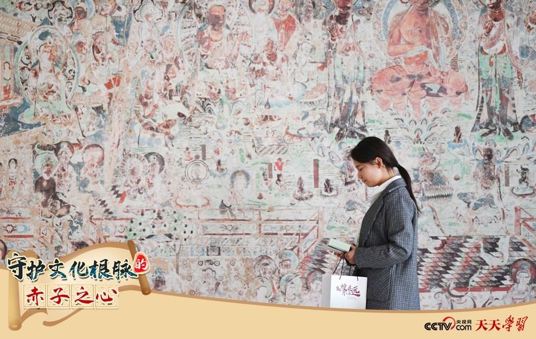 2023年4月25日，敦煌研究院文物數(shù)字化保護團隊創(chuàng)意營銷人員廖雪婷從一幅高保真復(fù)制壁畫前走過。
