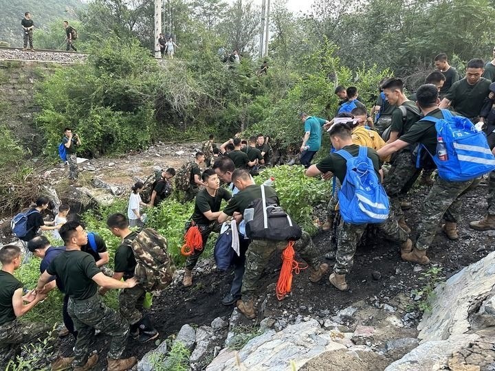 8月2日，Z180次受困列車的旅客在武警北京總隊機動第三支隊官兵的幫助下徒步前往轉(zhuǎn)運客車（手機照片）。新華社記者 王艷剛 攝