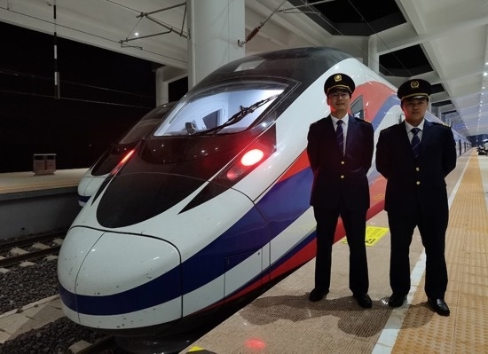 劉銀能（右一）與中國(guó)師父鄔俊鴻在動(dòng)車組前合影。受訪者供圖