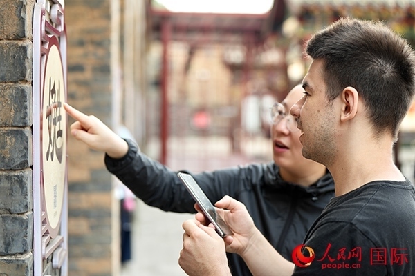 選手安德烈（俄羅斯）在老師指導(dǎo)下學(xué)習(xí)墻壁上張貼的生僻字。人民網(wǎng) 盧鵬宇攝