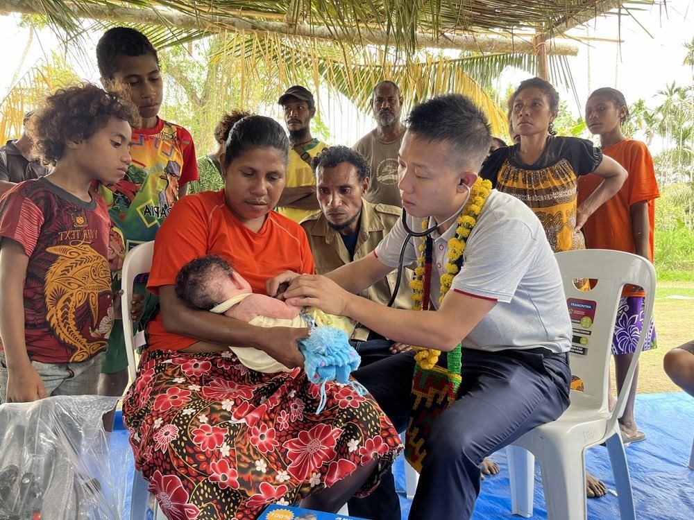 2023年8月5日，在巴布亞新幾內(nèi)亞中央省的一個(gè)村莊里，第12批援巴新中國(guó)醫(yī)療隊(duì)副隊(duì)長(zhǎng)、新生兒科副主任醫(yī)師劉振球?yàn)楫?dāng)?shù)貗雰郝?tīng)診檢查。新華社發(fā)（第12批援巴新中國(guó)醫(yī)療隊(duì)供圖）