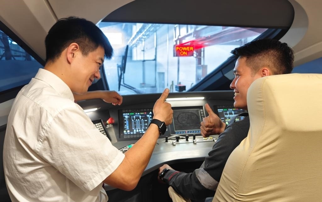 8月25日，在印度尼西亞萬隆的雅萬高鐵德卡魯爾動車所內，中國師傅穆振（左）在向印尼火車司機塞蒂亞萬講解動車組出庫前的上電作業(yè)。