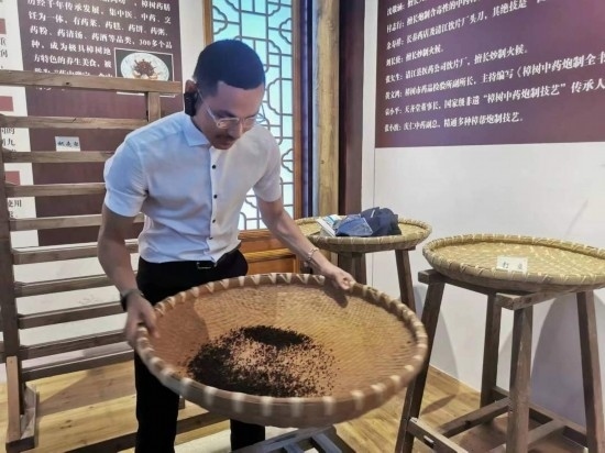 2023“一帶一路”媒體合作論壇聯(lián)合采訪團團員在非遺文化展示館體驗中藥炮制技藝。（本報記者 黃超攝）