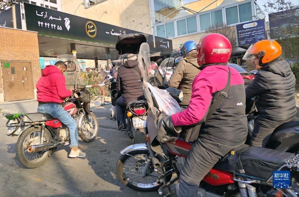 12月18日，摩托車在伊朗首都德黑蘭的一家加油站外等待加油。新華社記者 沙達提 攝