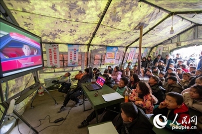 12月22日，在積石山縣大河家鎮(zhèn)大河村安置點，陸軍76集團軍某旅搭建的“臨時學?！眱?，小朋友正在看動畫片。人民網記者 翁奇羽攝