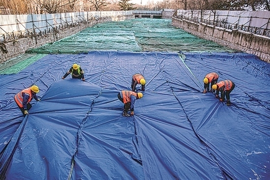 1月3日，房山區(qū)東風(fēng)街道，工人正在修復(fù)的河道內(nèi)給混凝土鋪設(shè)保溫布。