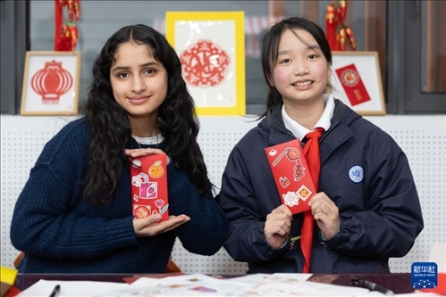 1月28日，美國馬斯卡廷中學學生（左）和復旦大學第二附屬學校學生展示互相送出的寫有寄語祝福的紅包。 新華社記者 王翔 攝