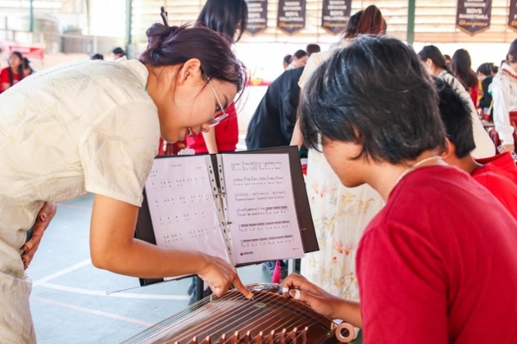 志愿者教師指導(dǎo)學(xué)生彈奏古箏?；顒又鬓k方供圖