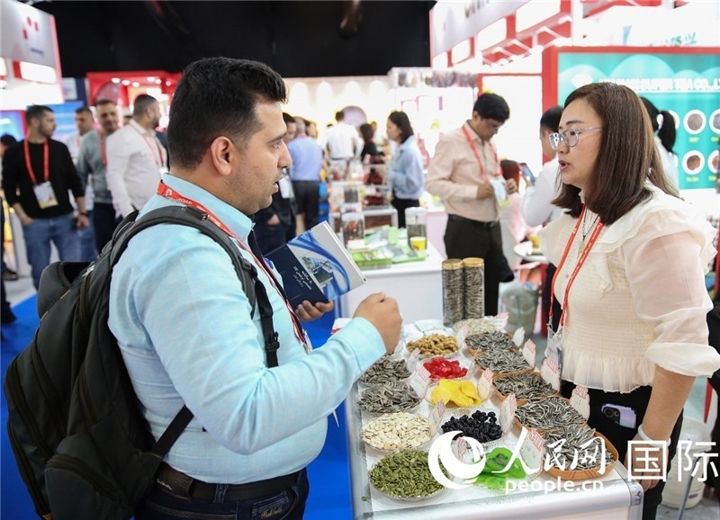 圖為一家中國干果參展企業(yè)代表與采購商洽談。人民網(wǎng) 塔里克·易卜拉欣攝