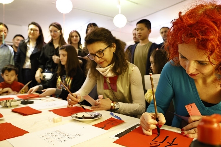 羅馬尼亞觀眾學(xué)習(xí)用毛筆寫“?！弊帧Ｖ袊?guó)文化中心供圖