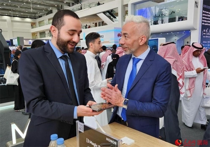 兩名觀眾在榮耀手機展臺前交流。人民網(wǎng)記者 管克江攝