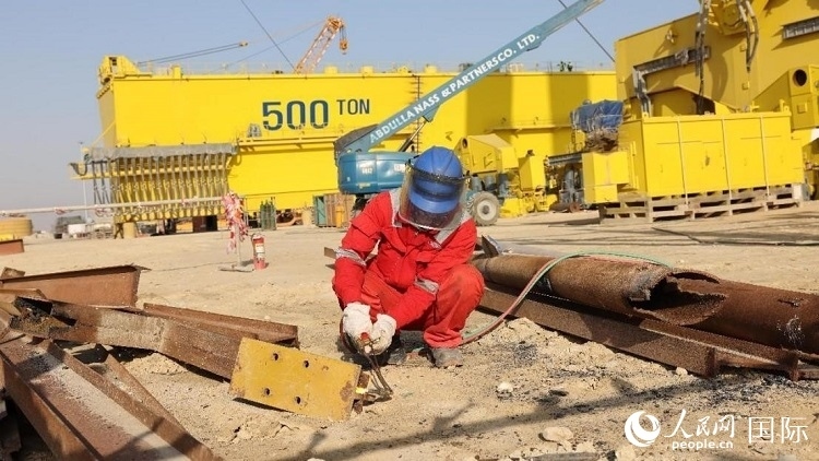 工人正在龍門吊吊裝現(xiàn)場切割金屬件。人民網(wǎng)記者管克江攝