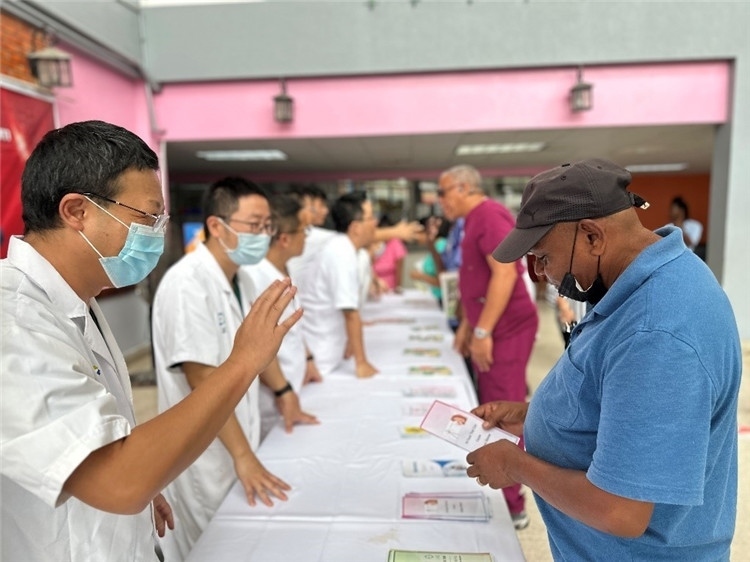 援圭醫(yī)療隊(duì)隊(duì)員們?cè)趩?dòng)儀式上為當(dāng)?shù)孛癖姺职l(fā)宣傳手冊(cè)。中國(guó)援助圭亞那醫(yī)療隊(duì)供圖