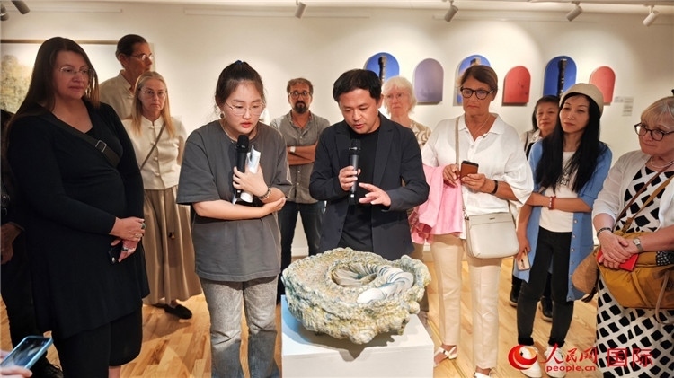 參展人、景德鎮(zhèn)陶瓷大學(xué)設(shè)計(jì)藝術(shù)學(xué)院副院長(zhǎng)余劍峰（中）向來賓介紹參展作品。人民網(wǎng)記者 殷淼攝