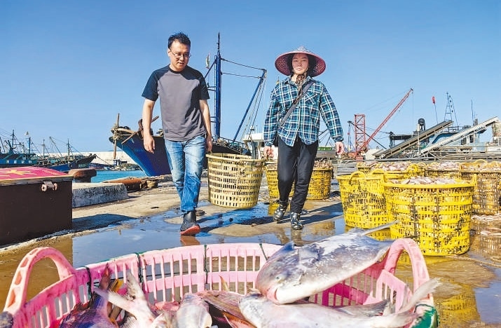 許小斌（左）和漁民一起搬運海鮮。本報記者 付 文攝