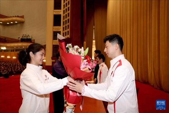 11月15日，一名學(xué)生代表在報告會上向乒乓球運動員馬龍（右）獻花。新華社記者 李明 攝