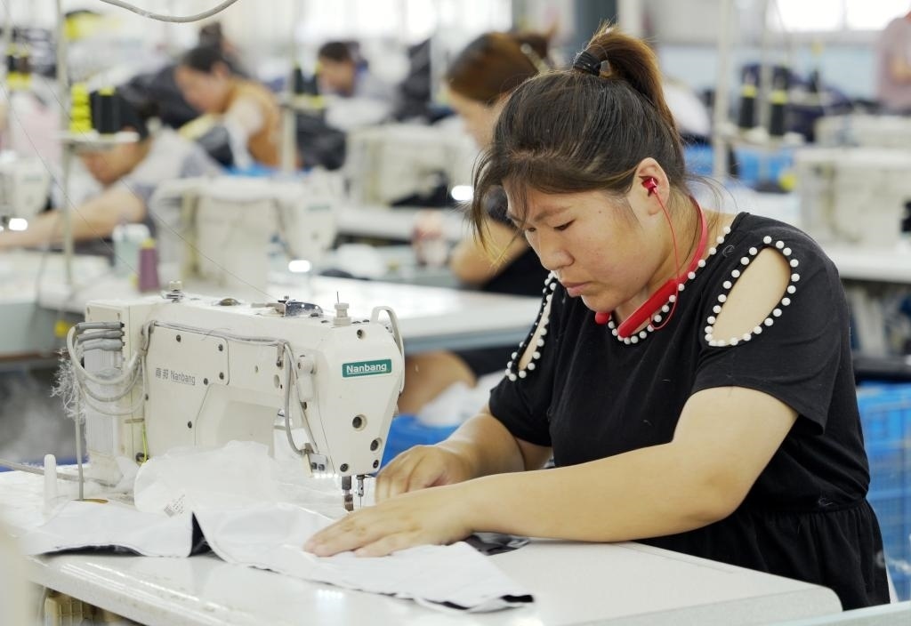 5月20日，村民在李寨村服裝加工廠內(nèi)忙碌。河南省周口市沈丘縣馮營鎮(zhèn)李寨村地處豫東平原。近年來，乘著脫貧攻堅與鄉(xiāng)村振興政策的東風(fēng)，李寨村積極探索產(chǎn)業(yè)發(fā)展模式，通過“龍頭企業(yè)+村集體經(jīng)濟(jì)+農(nóng)戶”的方式，逐漸發(fā)展形成肉牛養(yǎng)殖、設(shè)施農(nóng)業(yè)、服裝加工、康養(yǎng)民宿等產(chǎn)業(yè)，以產(chǎn)業(yè)振興助力鄉(xiāng)村振興。新華社記者 李嘉南 攝
