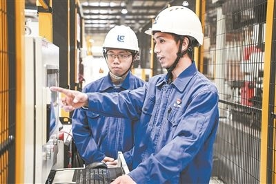 在廣西柳工機械股份有限公司生產(chǎn)車間內(nèi)，一名高級技師（右）給徒弟講解數(shù)控設(shè)備操作細節(jié)。新華社記者 曹祎銘攝