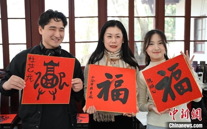 1月20日，外籍留學(xué)生和西泠印社社員李硯(中)展示各自創(chuàng)作的福貼。當(dāng)日，來(lái)自巴西、馬來(lái)西亞、加納、哈薩克斯坦的外籍留學(xué)生在浙江杭州西泠印社體驗(yàn)福貼、春聯(lián)和篆刻，感受古老的中國(guó)傳統(tǒng)文化。中新社記者 王剛 攝