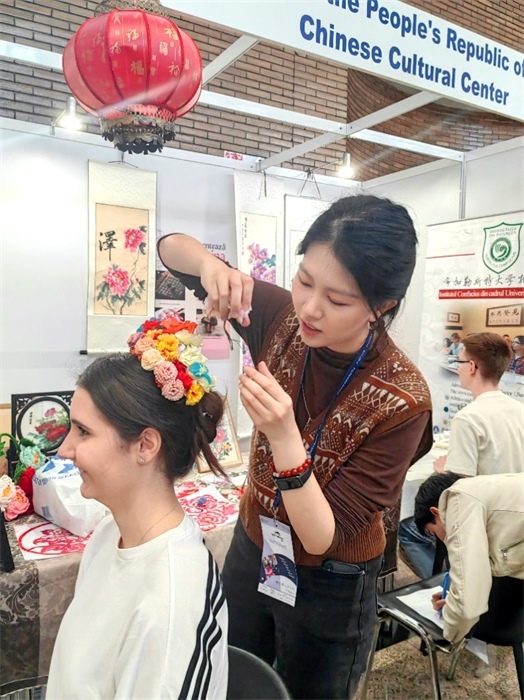 展覽正值羅馬尼亞迎春花節(jié)，國(guó)際中文教師志愿者潘婧穎向游客們介紹了國(guó)家非物質(zhì)文化遺產(chǎn)——福建泉州的簪花文化。布加勒斯特大學(xué)孔子學(xué)院供圖。