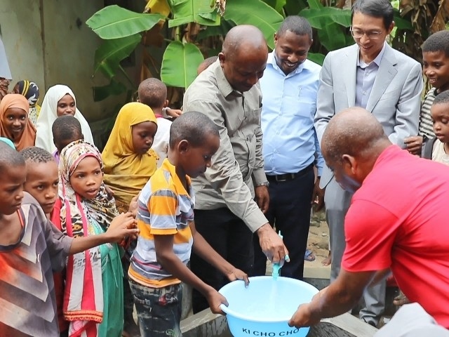 在日前舉行的安全供水工程揭牌儀式上，當?shù)匦∨笥言诠┧c接水。 施亮攝