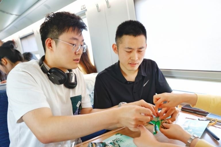 G232次旅客親手制作端午荷包和五彩繩。王磊攝